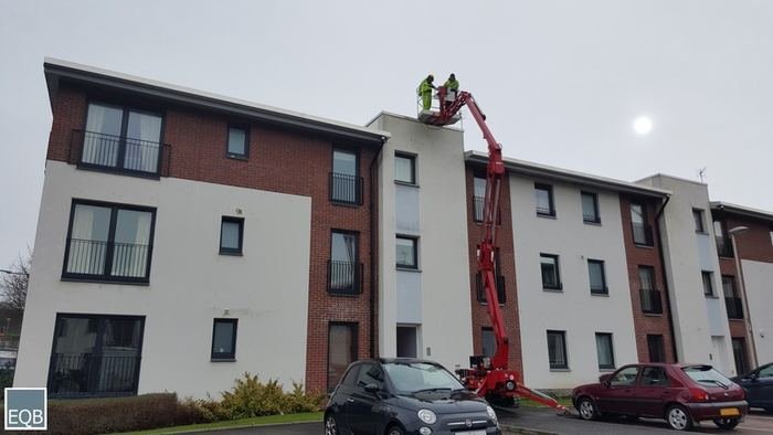 Cherry-picker access platform working on a modern Edinburgh apartment block roofline
