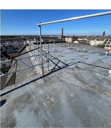 Flat roof waterproofing in progress with safety railing and Edinburgh skyline